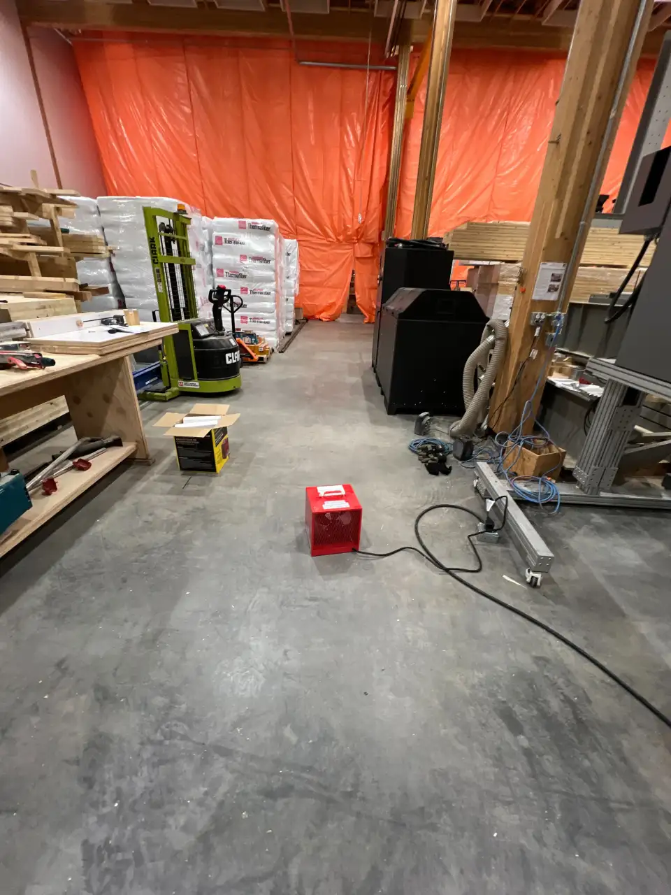 A view on the interior of the building showing the hoarding to separate the wall to be replaced from the rest of the building, and the insulation (bags on the left), and some of the equipment that was subjected to flooding when the sprinkler went off (black thing on the right).